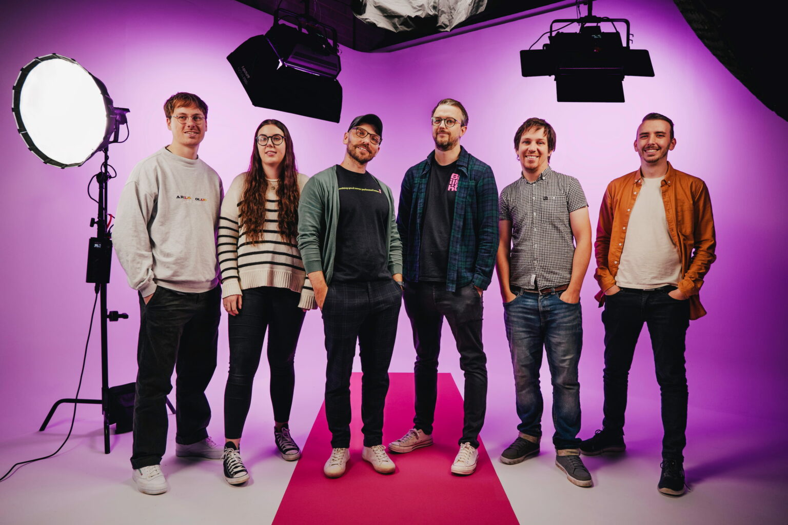Employees at visual marketing agency Briight standing on a training videography set in front of a purple background