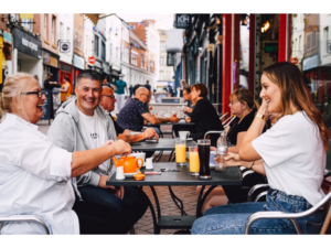 Four people smiling sat around a table in the Cathedral Quarter Derby