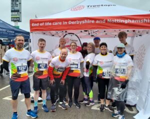 Ten runners standing in front of a Treetops Hospice stand
