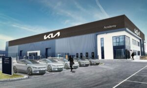 A warehouse featuring the Kia logo on the left hand side with Kia cars parked in front of it